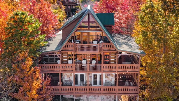 Eine zweistöckige Blockhütte mit Balkon, umgeben von Herbstlaub.