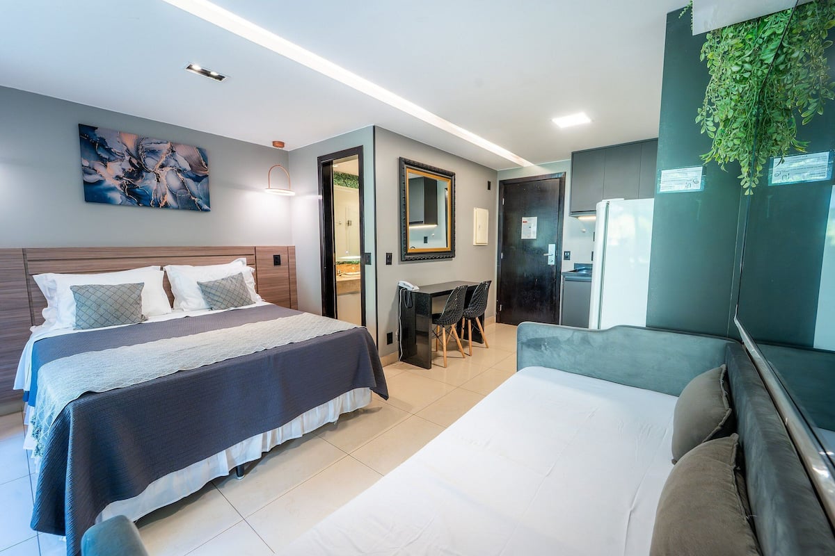 A modern hotel room with two beds, a desk, and a seating area.