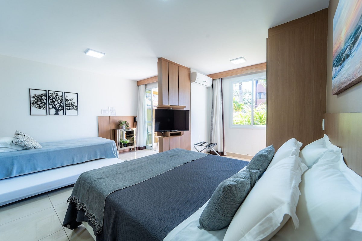 A modern hotel room with a large bed, a smaller bed, a TV, and a window with curtains.