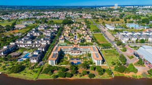An aerial view of a coastal resort with multiple buildings, a central swimming pool, and surrounding greenery. - The Sun flat (Brasília)