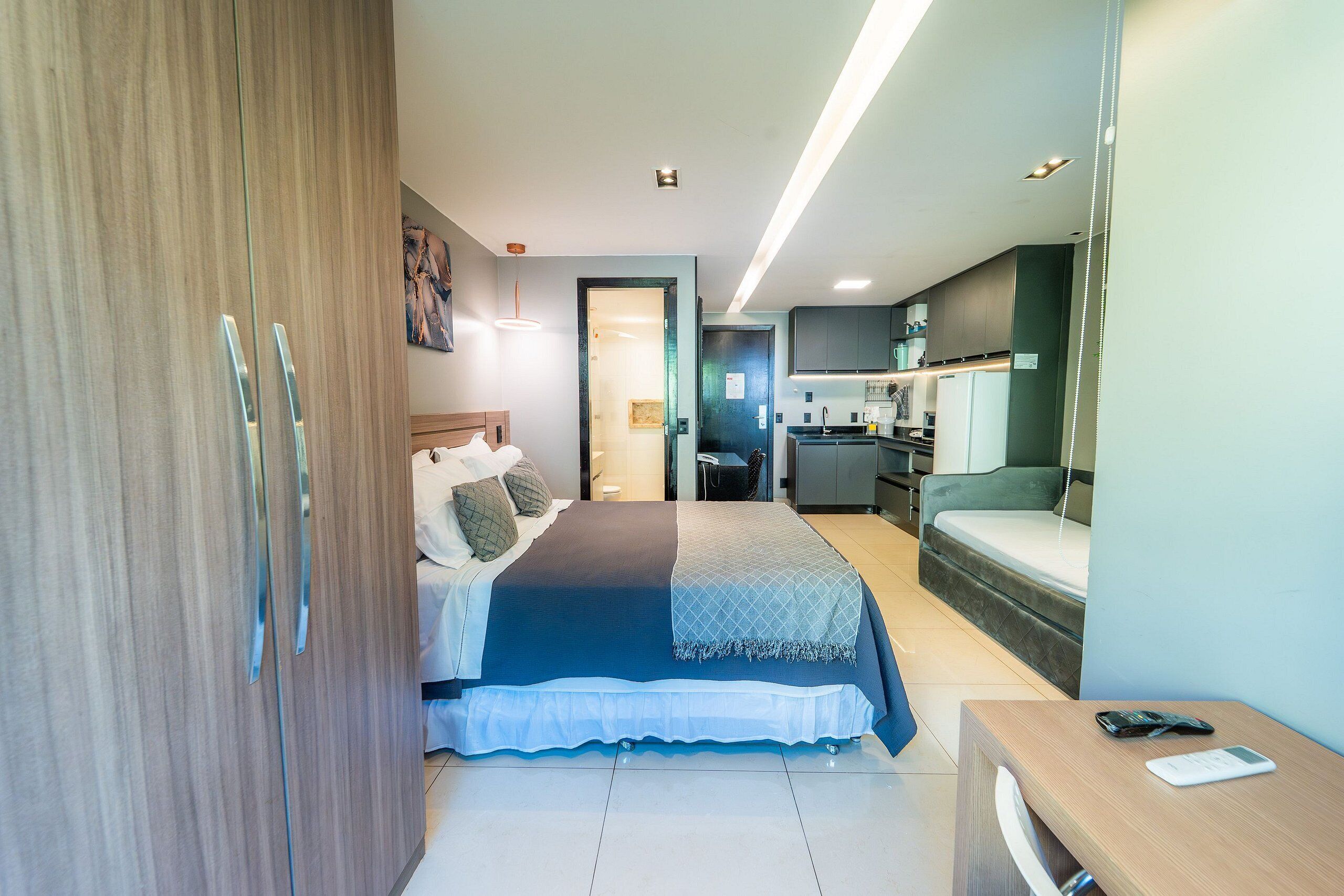 Une chambre d’hôtel moderne équipée d’un lit, d’un bureau, d’une armoire et d’une kitchenette.