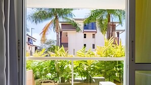 A balcony with a round table and chairs, a view of a residential area with houses and greenery. - The Sun flat (Brasília)