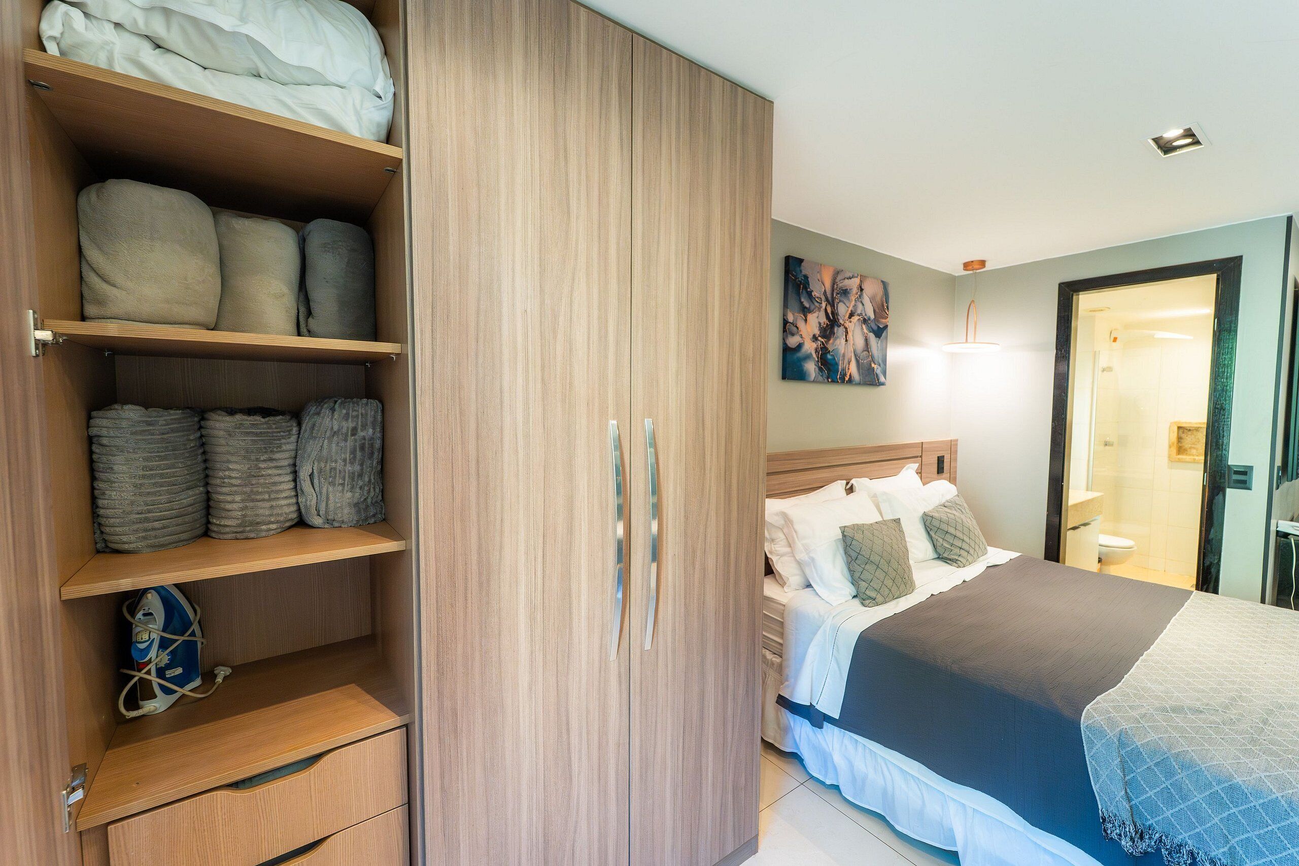 Une chambre à coucher avec un lit, une armoire et une salle de bain visible à travers une porte ouverte.
