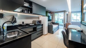 Een moderne keuken met een ingebouwde magnetron, een spoelbak en een koelkast. Er is een eethoek met een tafel en stoelen.