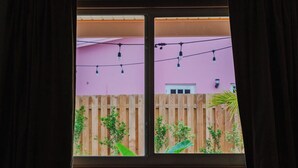 Ein Fenster mit zwei Scheiben, durch die ein Holenzaun und viel Grün zu sehen ist.