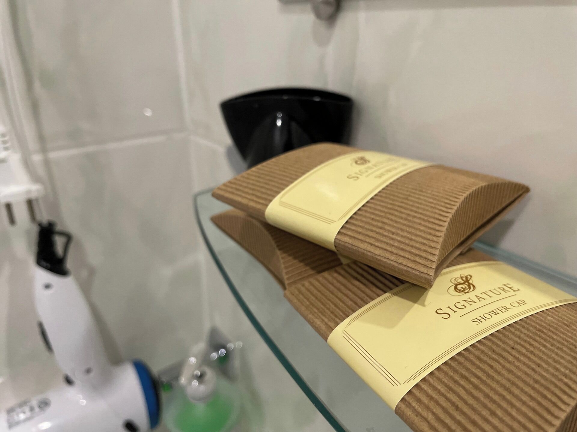 Two shower caps on a glass shelf in a bathroom.