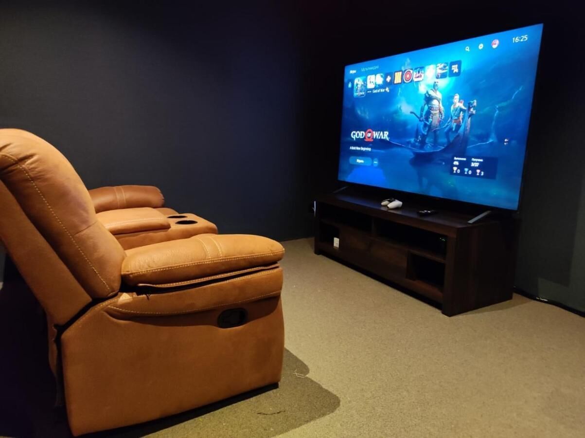 A home theater setup with a large flat-screen TV, a leather reclining chair, and a dark entertainment unit.