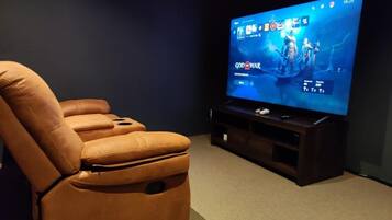 Sistema de cine en casa con un televisor de pantalla plana grande, un sillón de cuero reclinable y un mueble multimedia oscuro.