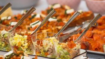 A buffet with various dishes, including a salad with shredded cheese and a dish with smoked salmon.