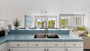 Een moderne keuken met een blauw aanrecht, witte kasten en een roestvrijstalen spoelbak.