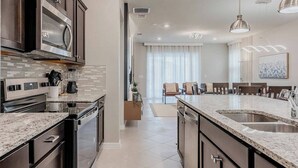 A modern kitchen with dark cabinetry, granite countertops, and stainless steel appliances.