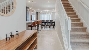 A modern interior with a staircase, a dining area, and a reception desk.