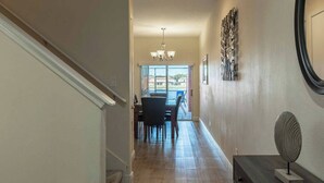 A hallway with a dining area, a chandelier, and a decorative wall piece. - 4BR house with pool near Disney area (Kissimmee)