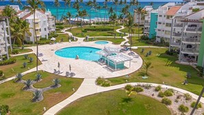 A resort with a central pool, palm trees, and a view of the ocean. - On Bavaro Beach - Secure, Gated Condo Community. In Center of Bavaro-Punta Cana (La Altagracia Province)