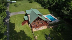 A large, two-story log cabin with a green roof, a swimming pool, and a deck area with outdoor furniture. - A Slice of Salisbury, Pool,Hot Tub, 10 acres (Salisbury)