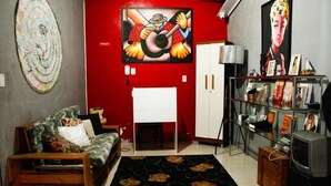 Un salon avec un mur d’accent rouge, un canapé, une petite table, un téléviseur et une bibliothèque.
