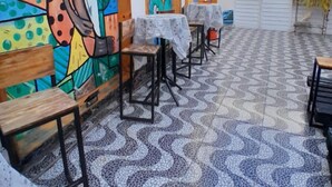 Un espace extérieur aménagé en terrasse, avec des tables et des chaises, un sol carrelé et des peintures murales colorées.
