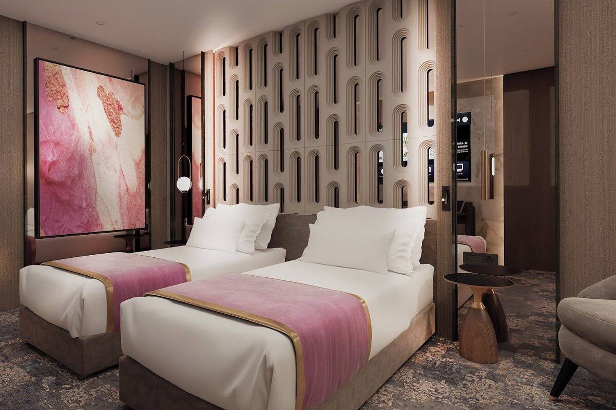 A hotel room with two beds, a large artwork on the wall, a modern wall panel, and a small table with a lamp.