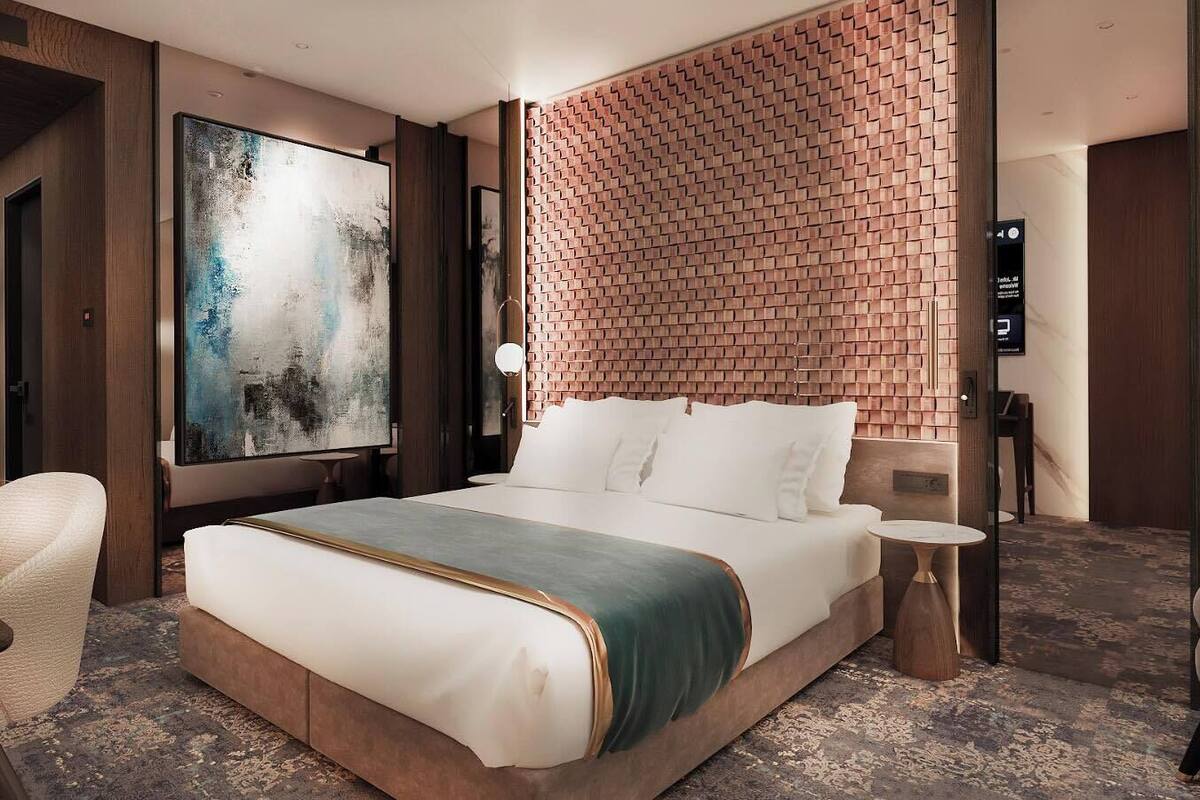 A hotel room with a large bed, a brick-patterned headboard, a large abstract painting, and a modern design.