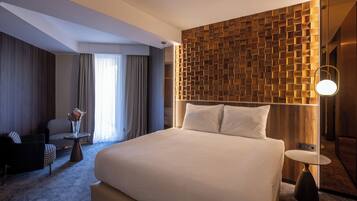 Una camera d'albergo con un letto grande, una parete decorata in legno, un tavolino rotondo e un divano.