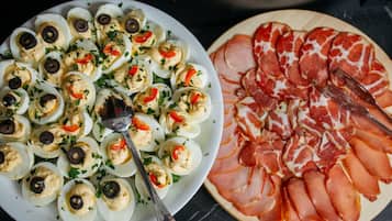 Une assiette d’œufs mimosa décorée d’herbes et une assiette de tranches de jambon cru.