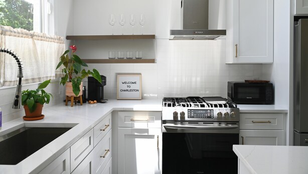 A modern kitchen with white cabinetry, a gas stove, a microwave, and a sink. - Charming 2-bedroom house in beautiful Charleston with full kitchen, AC, patio (Charleston)
