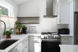 Une cuisine moderne avec des meubles blancs, une cuisinière à gaz, un four à micro-ondes et un évier.