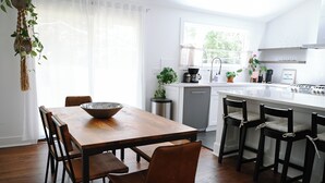 A modern kitchen with a wooden dining table, chairs, and a coffee station. - Charming 2-bedroom house in beautiful Charleston with full kitchen, AC, patio (Charleston)