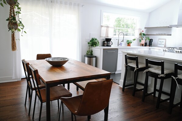 Una cocina moderna con una mesa de comedor de madera, sillas y una estación de café.
