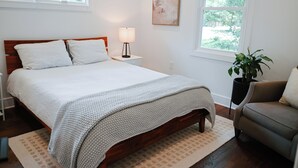 A neatly arranged bedroom with a large bed, bedside tables, a chair, and a potted plant. - Charming 2-bedroom house in beautiful Charleston with full kitchen, AC, patio (Charleston)