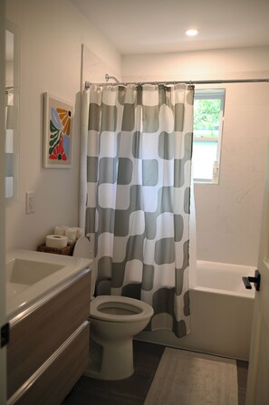Un baño con inodoro, bañera y cortina de ducha.
