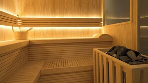 Un sauna en bois avec un banc incliné, une petite table en bois et un récipient rempli de pierres.