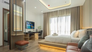 Une chambre d’hôtel moderne équipée d’un lit, d’un coin salon, d’un bureau et d’une télévision.