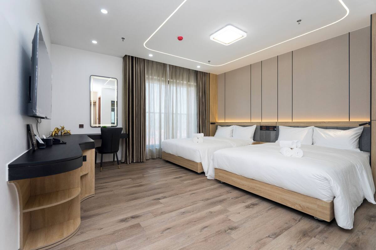 Ett modernt hotellrum med två sängar, ett skrivbord och en TV.