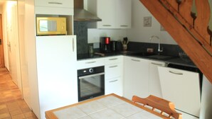A compact kitchen with white cabinets, a microwave, a stove, and a sink.