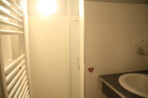 A bathroom with white tiles, a white sink, and a heart-shaped decoration on the wall. - Chalet de L'oy Oy16 Nature & Mountain 6 Pers (Chatel)