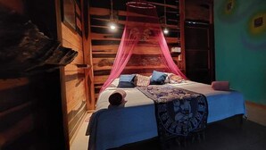 A room with a bed under a pink canopy, wooden walls, and a colorful wall mural. - Cabañas Huay (Huay-Pix)