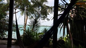 A tropical setting with a view of the sea, surrounded by dense foliage and palm trees. - Cabañas Huay (Huay-Pix)