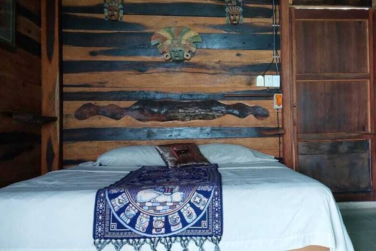 Una habitación con cama, cabecera de madera y pared azul.