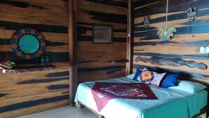 A wooden cabin-style room with a bed, a wall clock, and a small shelf with bottles. - Cabañas Huay (Huay-Pix)