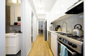 Une cuisine moderne avec des armoires blanches, une cuisinière en acier inoxydable et un plancher en bois.