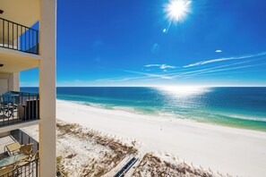 Een strandhotel met een balkon met uitzicht op de oceaan, een zandstrand en heldere lucht.