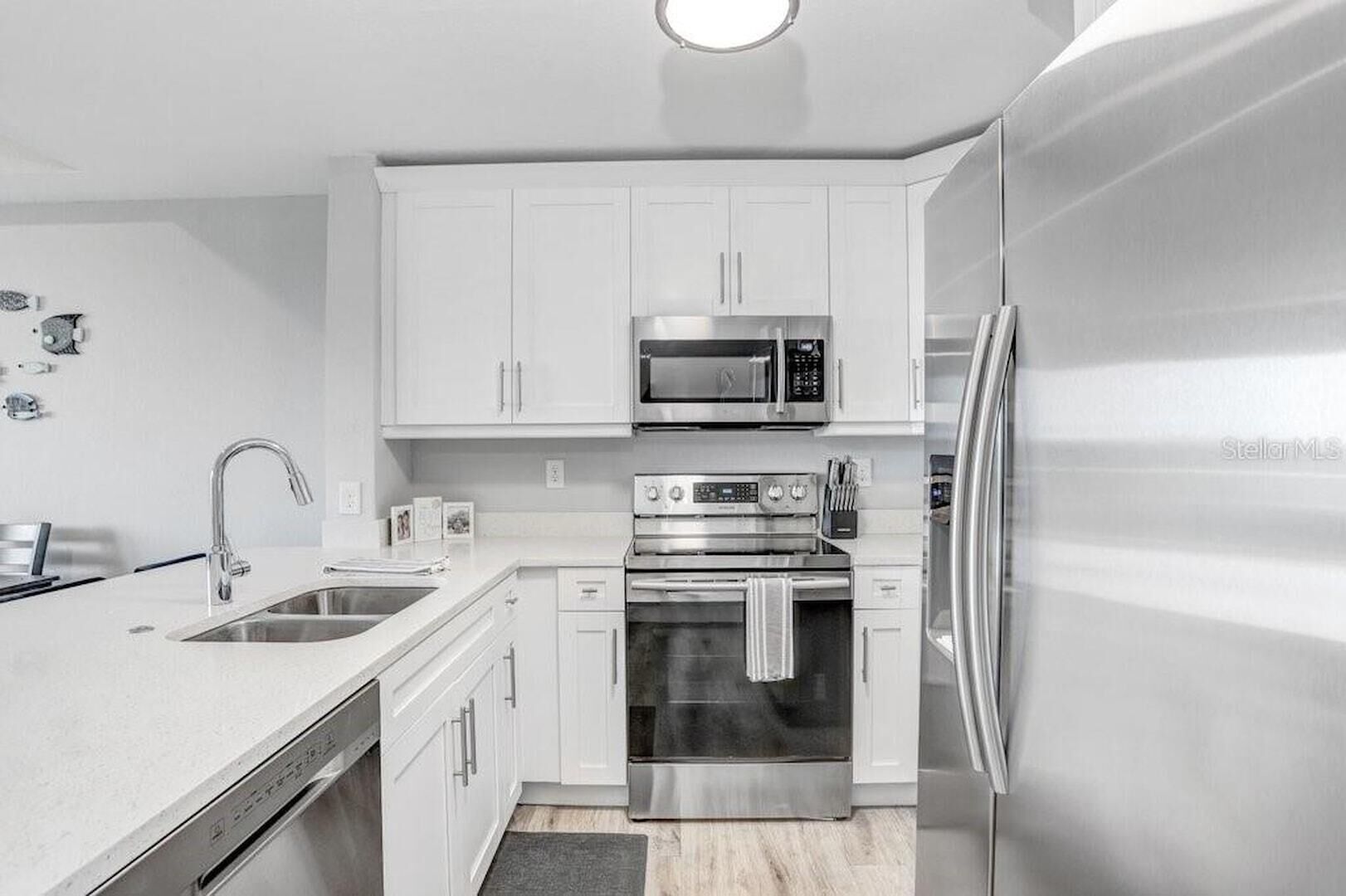 A modern kitchen with white cabinets, stainless steel appliances, and a built-in oven.