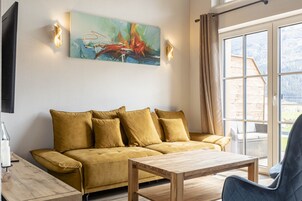 A modern living room with a sofa, a wooden coffee table, and a painting on the wall.