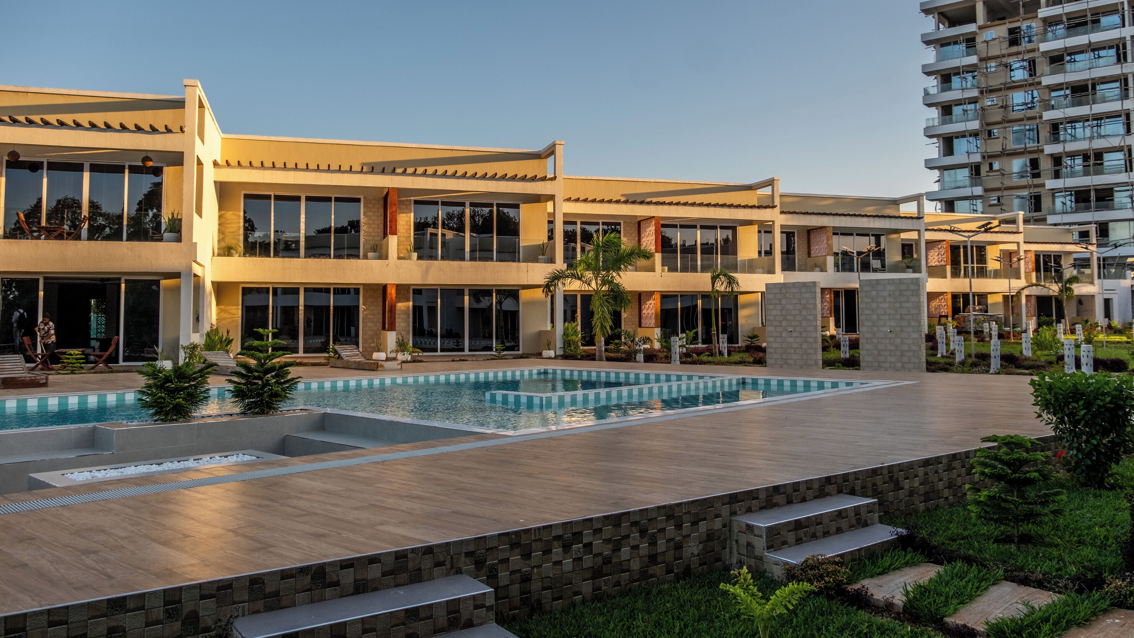 A modern residential building with a swimming pool, outdoor seating, and a well-maintained garden.