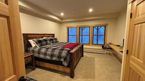 A bedroom with a bed, a desk, and a window. - Spacious 4-bedroom Ski- in/ Ski-out condo in enchanting Sunday River w/ Hot Tub  (Newry)
