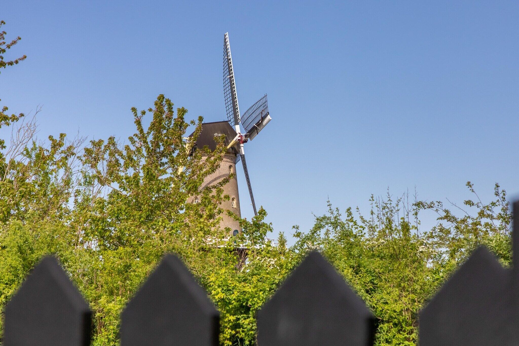 A windmill with a tower, surrounded by greenery.