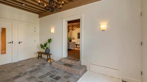 A spacious entryway with a tiled floor, a wooden bench, and a potted plant. - Farmhouse in Zeeland with Windmill Views (Heinkenszand)