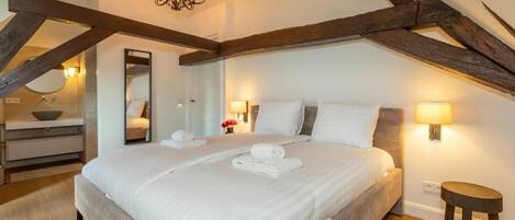 Une chambre à coucher avec un grand lit, des poutres en bois, un lustre et des lampes de chevet.