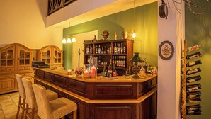 A bar area with wooden bar counter, bar stools, and a wine rack. - Pensiunea Sibiel (Sibiel)